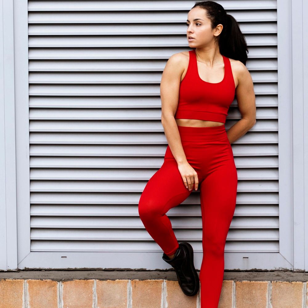 Woman in red athletic wear sitting against a metallic shutter.